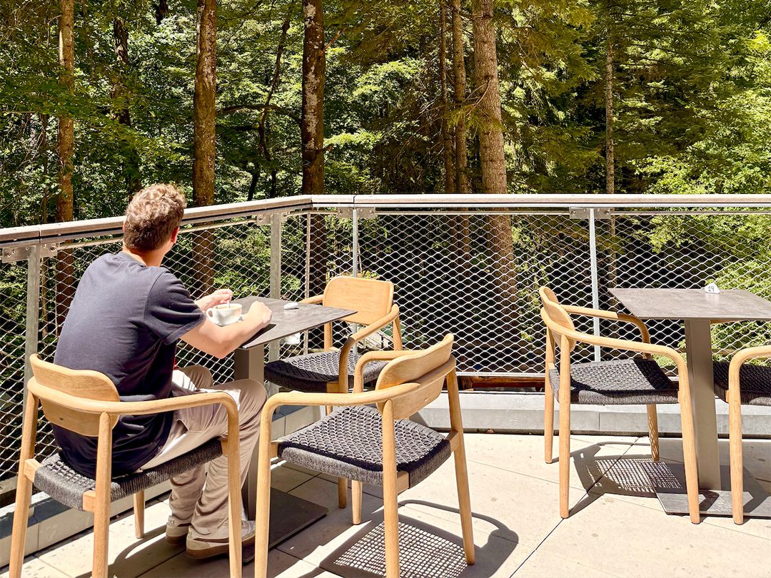 Personne prenant son café depuis la terrasse de la buvette Roc' n Snack des Grottes de Vallorbe